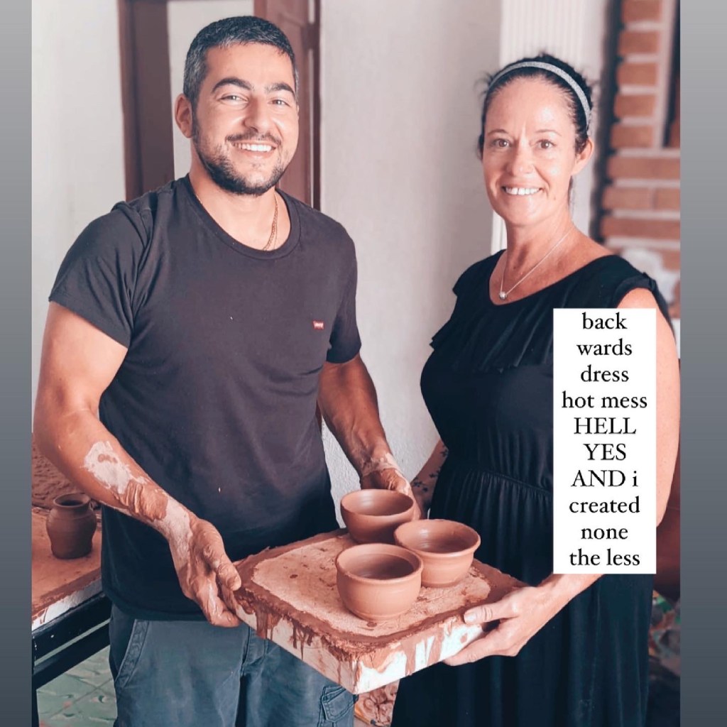 Couple man and woman holding a slab with with pottery that they made with clay on their hands showing what they created with 3 bowls in a rustic pottery class room both smiling with the text backwards dress hot mess hell yes and I created none the less on the image
